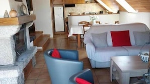 Una sala de estar acogedora con chimenea, un comedor y una cocina al fondo.