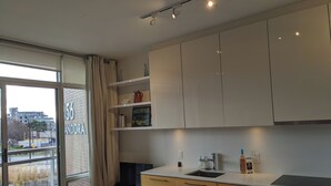 Una cocina moderna con armarios blancos, horno empotrado y ventana con vistas al exterior.