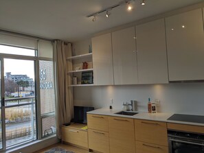 A modern kitchen with white cabinets, a built-in oven, and a window with a view of the outside. - Bright waterfront condo in the heart of Victoria (Victoria)