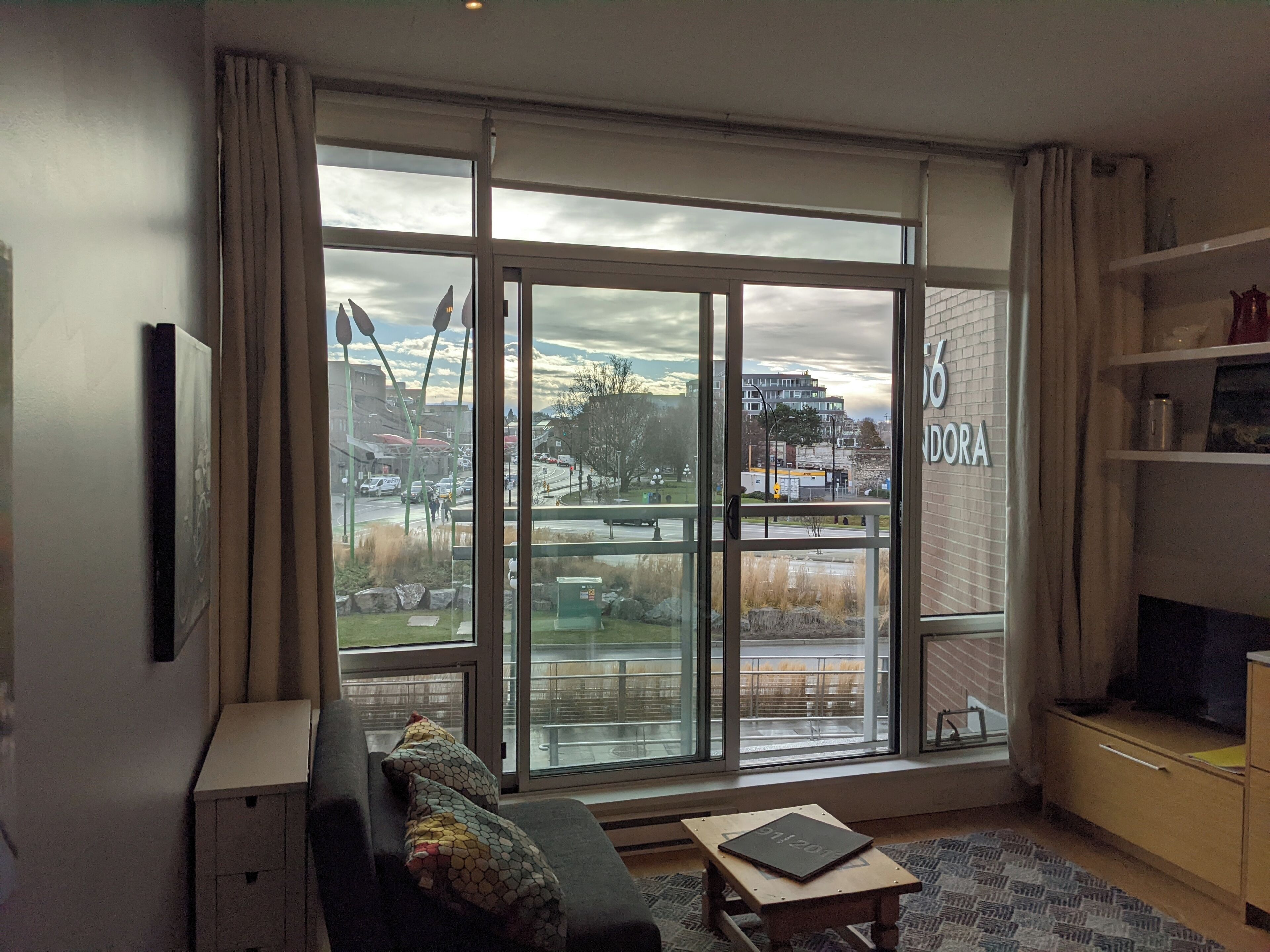 Ein Zimmer mit großem Fenster, einer Couch, einem kleinen Tisch und einem Fernseher.