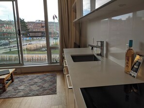 A modern kitchen with a large window, a sink, and a bottle of liquor on the counter. - Bright waterfront condo in the heart of Victoria (Victoria)