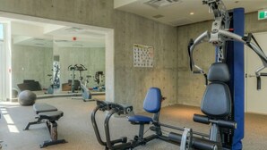 Un gimnasio con equipo de ejercicio, una banca y un calendario en la pared.