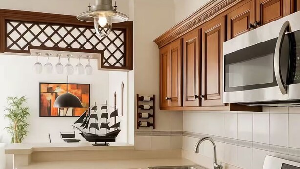 A kitchen with wooden cabinets, a stainless steel sink, a stove, and a microwave. - Comfort and peace of mind (Santo Domingo Este)
