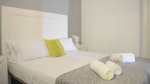 Een hotelkamer met een bed, een nachtkastje en een opgerolde handdoek op het bed.