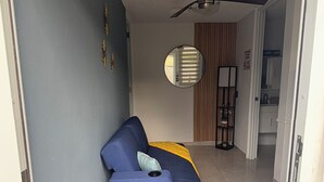 Quarto com sofá azul, uma mesinha, espelho e painel de parede de madeira.