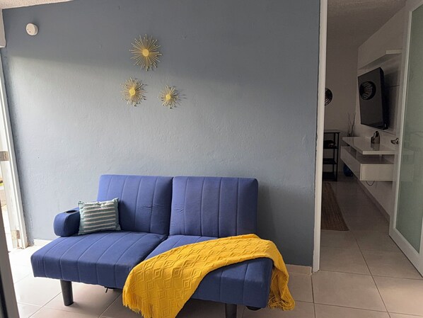 Un canapé bleu avec un plaid jaune, un petit coussin et des éléments décoratifs muraux.