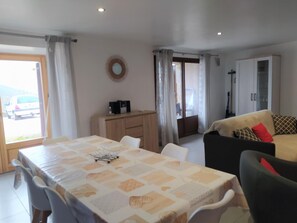 A dining area with a table and chairs, a sofa, a cabinet, and a view through a door. - Gîte Lezinio - LE PONT-DE-MONTVERT (LE PONT-DE-MONTVERT)