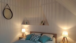 Ein Schlafzimmer mit einem Bett, zwei Nachttischen mit Lampen, einem Wandspiegel und einem Regal mit Dekoration.