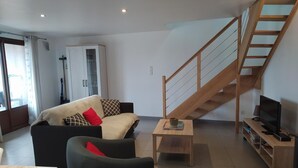 Ein Wohnzimmer mit einer Couch, einem Couchtisch, einer TV-Konsole und einer Holztreppe.