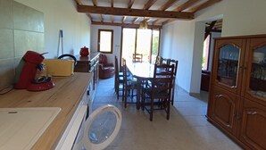 Une cuisine avec une table à manger, des chaises, des meubles de rangement en bois et une fenêtre.