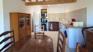 Une cuisine avec des poutres en bois, une table à manger avec des chaises, un four à micro-ondes, un four traditionnel, un évier et un grille-pain.