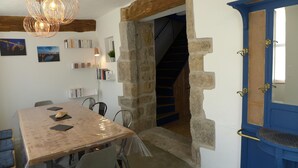 Un comedor con una mesa de madera, sillas y una araña. Una escalera conduce a un nivel superior.