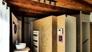 Un baño con techo de madera, un lavabo blanco, un perchero y una cortina de ducha.