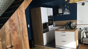 Una cocina moderna con armarios blancos, encimera de madera y horno empotrado.