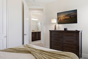 A bedroom with a bed, a dresser, a mirror, and a painting on the wall. - Comfort 6BR Getaway Private Pool Great Location (Kissimmee)