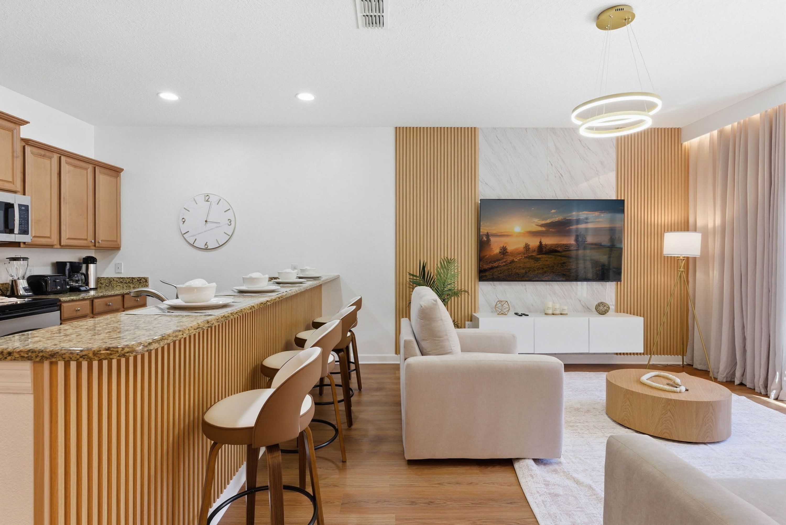 Una cocina moderna con una isla central, un área de comedor con taburetes de bar, un sofá y una mesa de centro redonda.