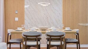 Zona de menjador amb paret de marbre, revestiment de fusta i un llum modern.