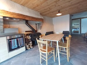 Ein rustikales Interieur mit einem Holztisch und -stühlen, einem Herd und einem Kamin.