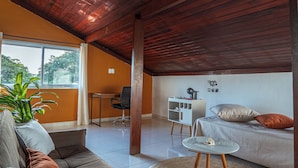 A modern living room with a brown sofa, a round coffee table, and a white chair. - Souza Apart 2 - Apartamentos completos (Sao Thome das Letras)