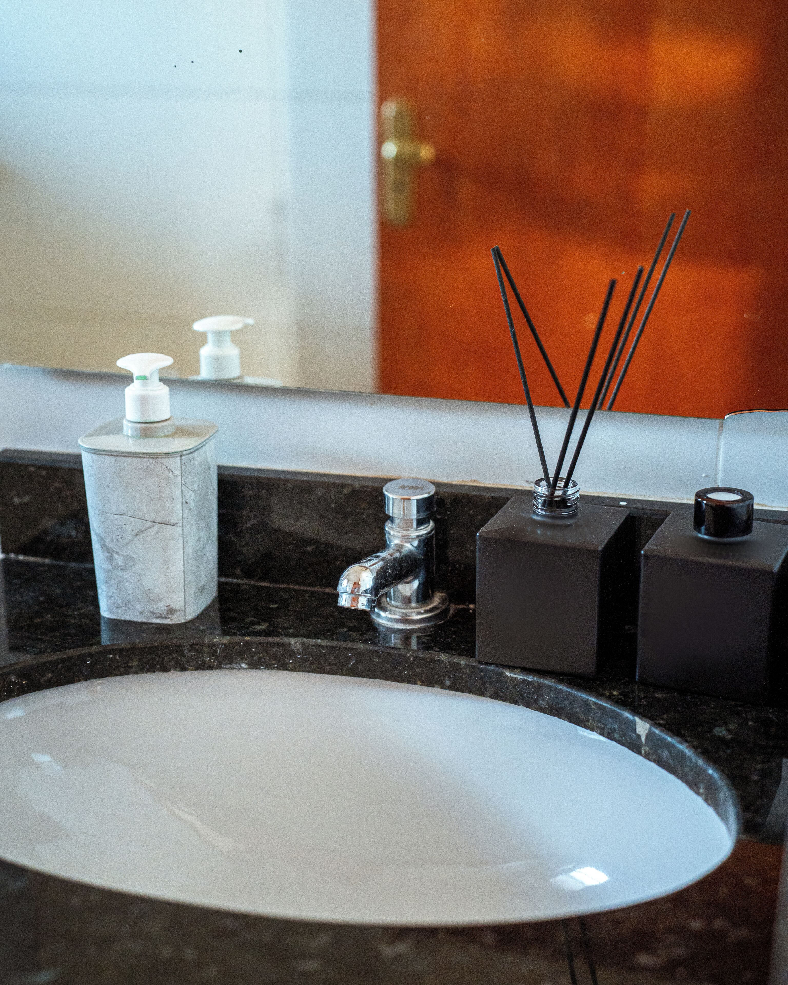 A bathroom sink with a marble countertop, a soap dispenser, a faucet, and a mirror.