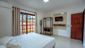 A hotel room with a bed, a TV mounted on the wall, and a wooden door. - Souza Apart 2 - Apartamentos completos (Sao Thome das Letras)