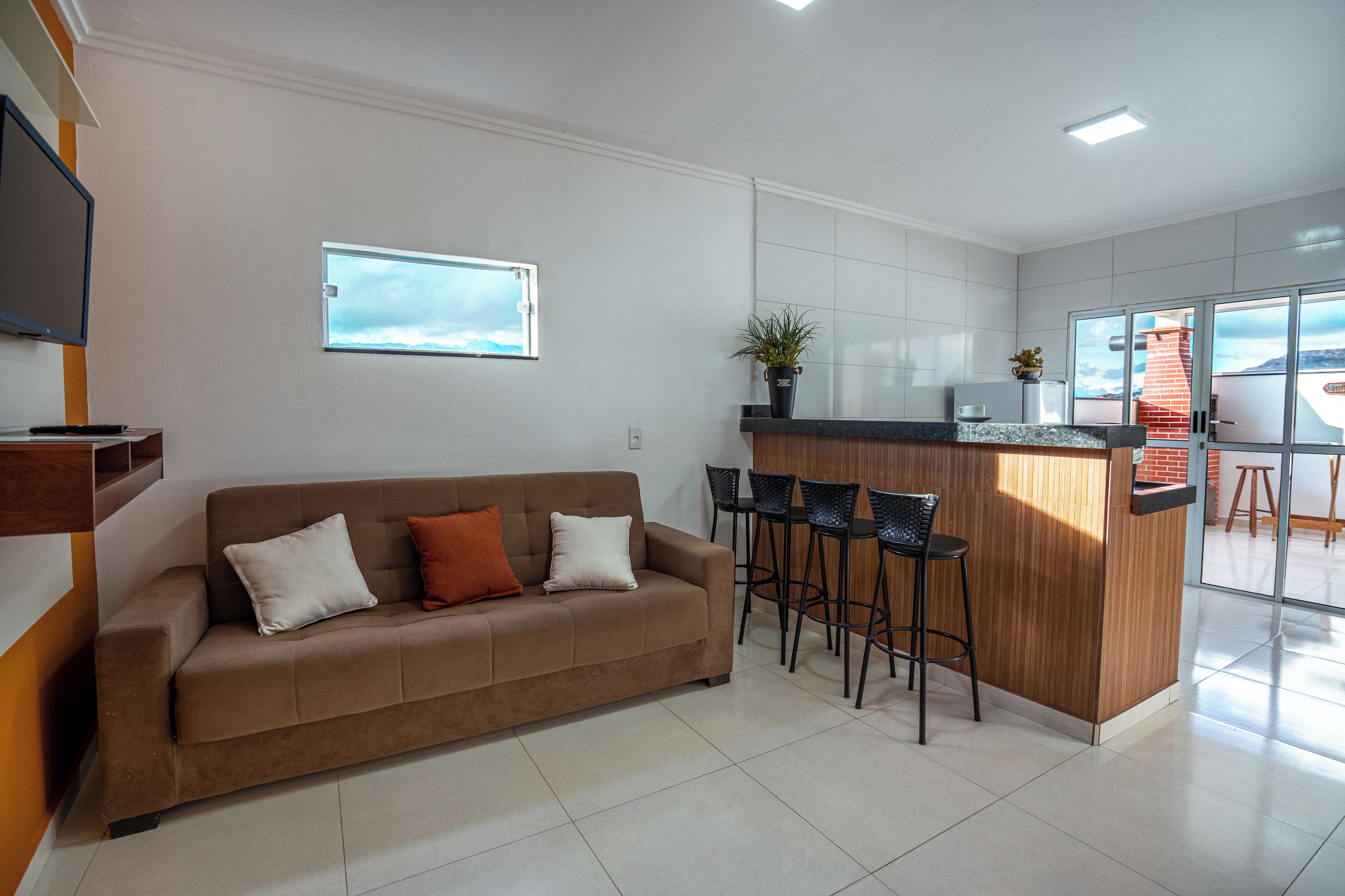A modern kitchen with a wooden island, bar stools, and a large window.