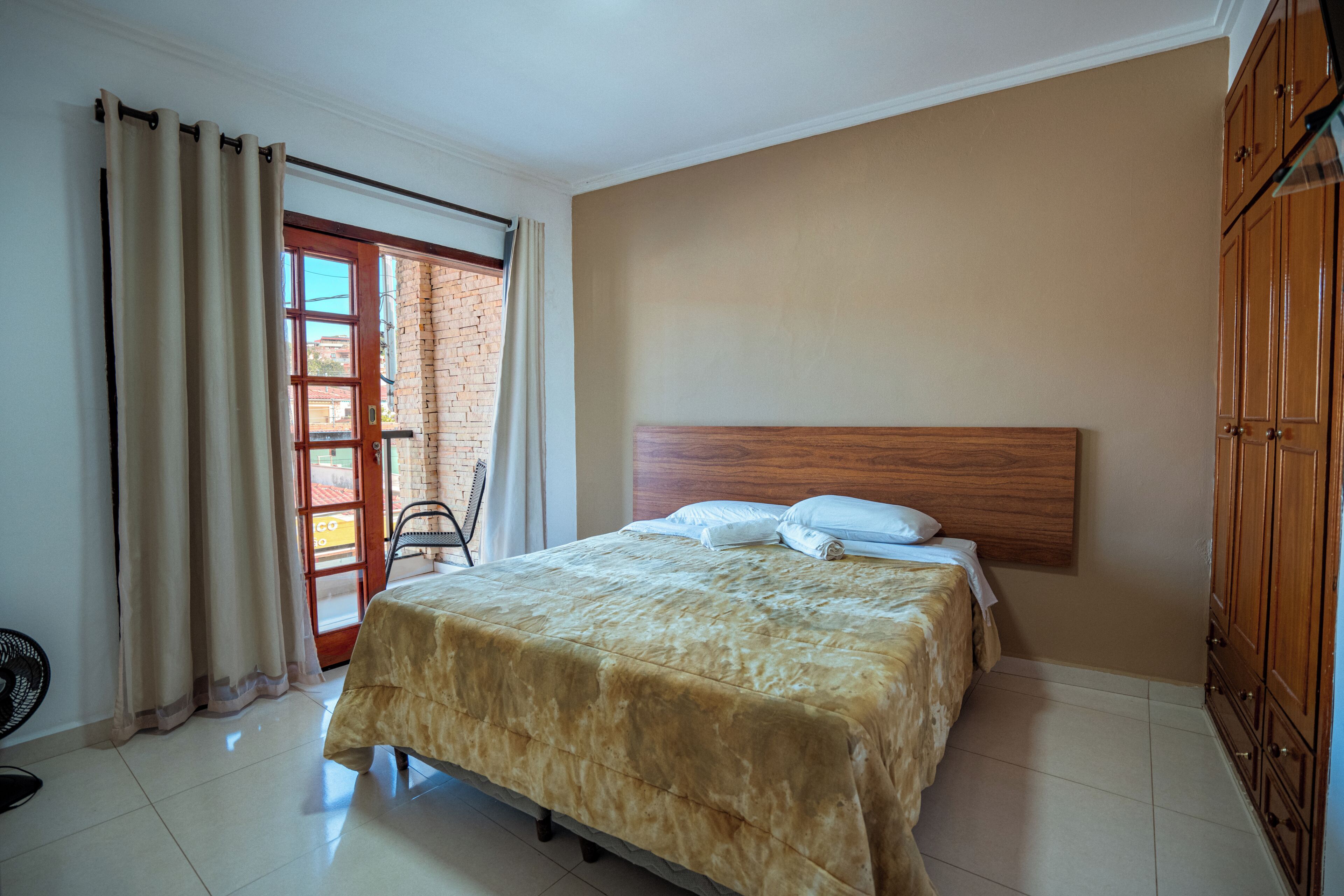 A bedroom with a bed, wooden headboard, and a view through a glass door.