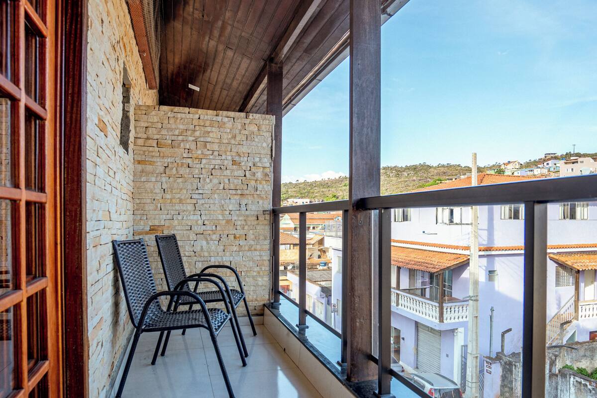 Un balcon donnant sur des immeubles, un mur de briques et deux chaises.