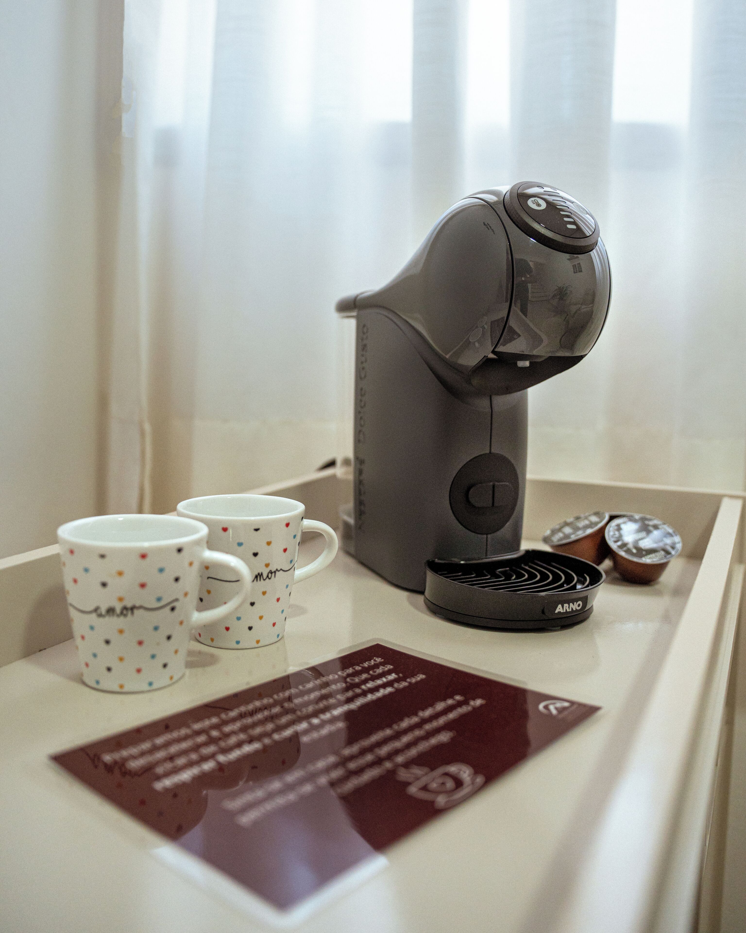 Una cafetera, dos tazas y una tarjeta de menú sobre una mesa.