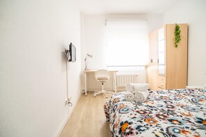Una camera da letto con un letto, una scrivania, una sedia, un termosifone e un armadio.