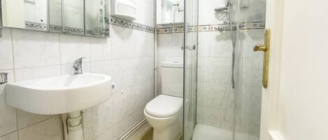 A bathroom with a sink, toilet, and glass-enclosed shower.