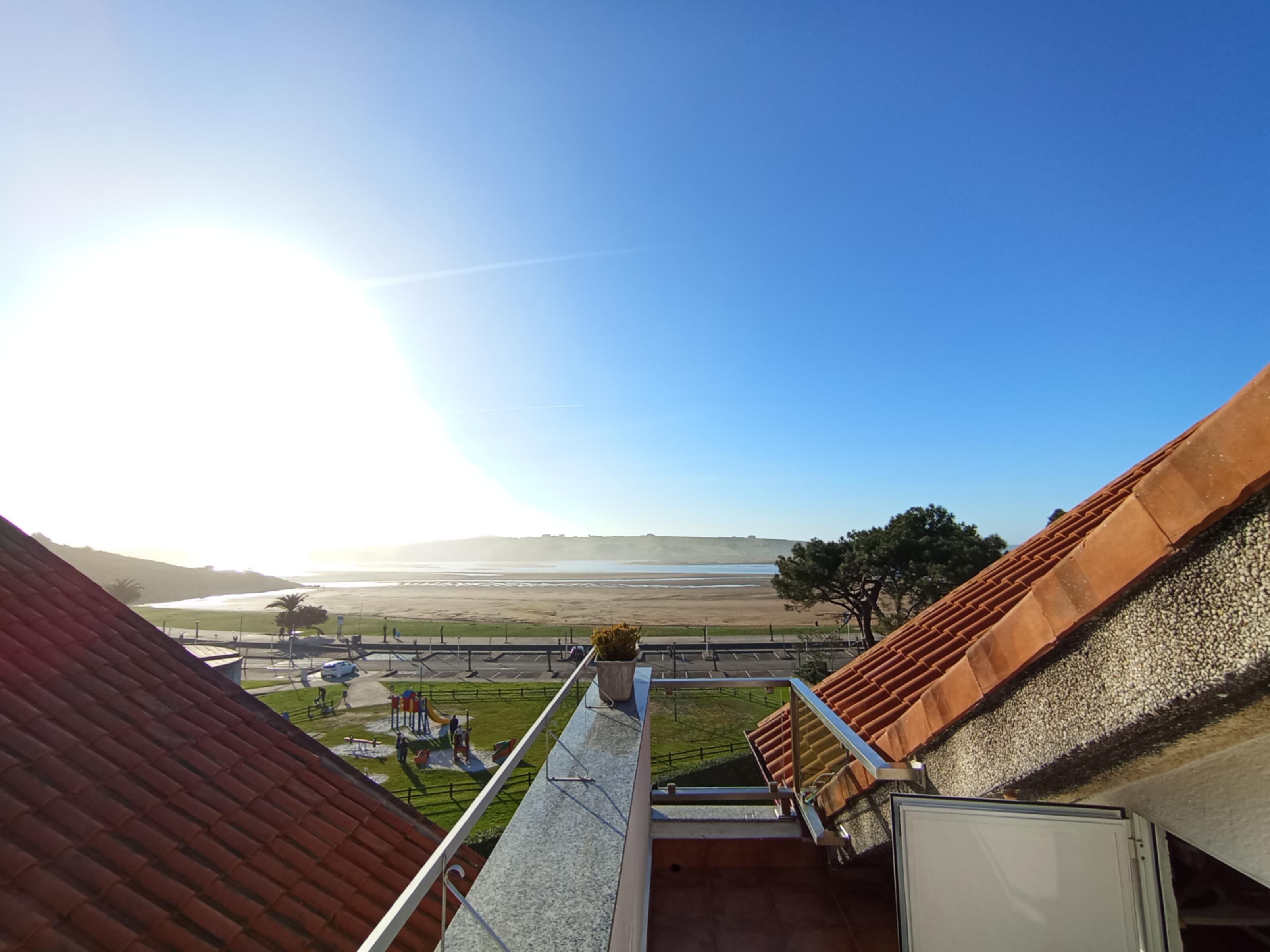 Vista desde un balcón sobre una playa con cielo despejado.