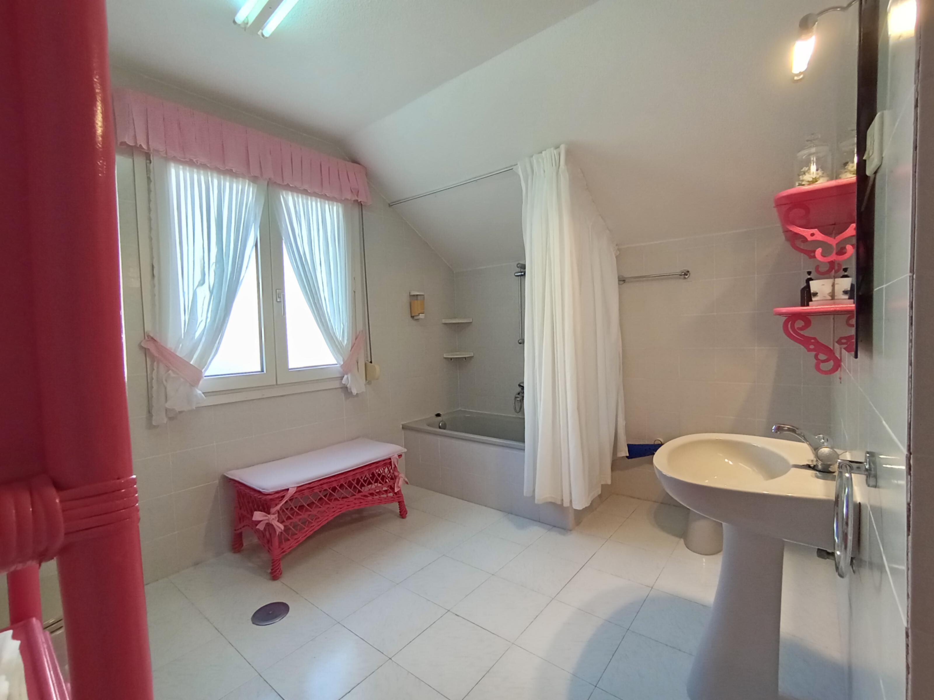 A bathroom with a bench, a bathtub, a sink, and a shower.