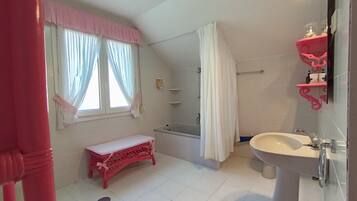 A bathroom with a bench, a bathtub, a sink, and a shower.