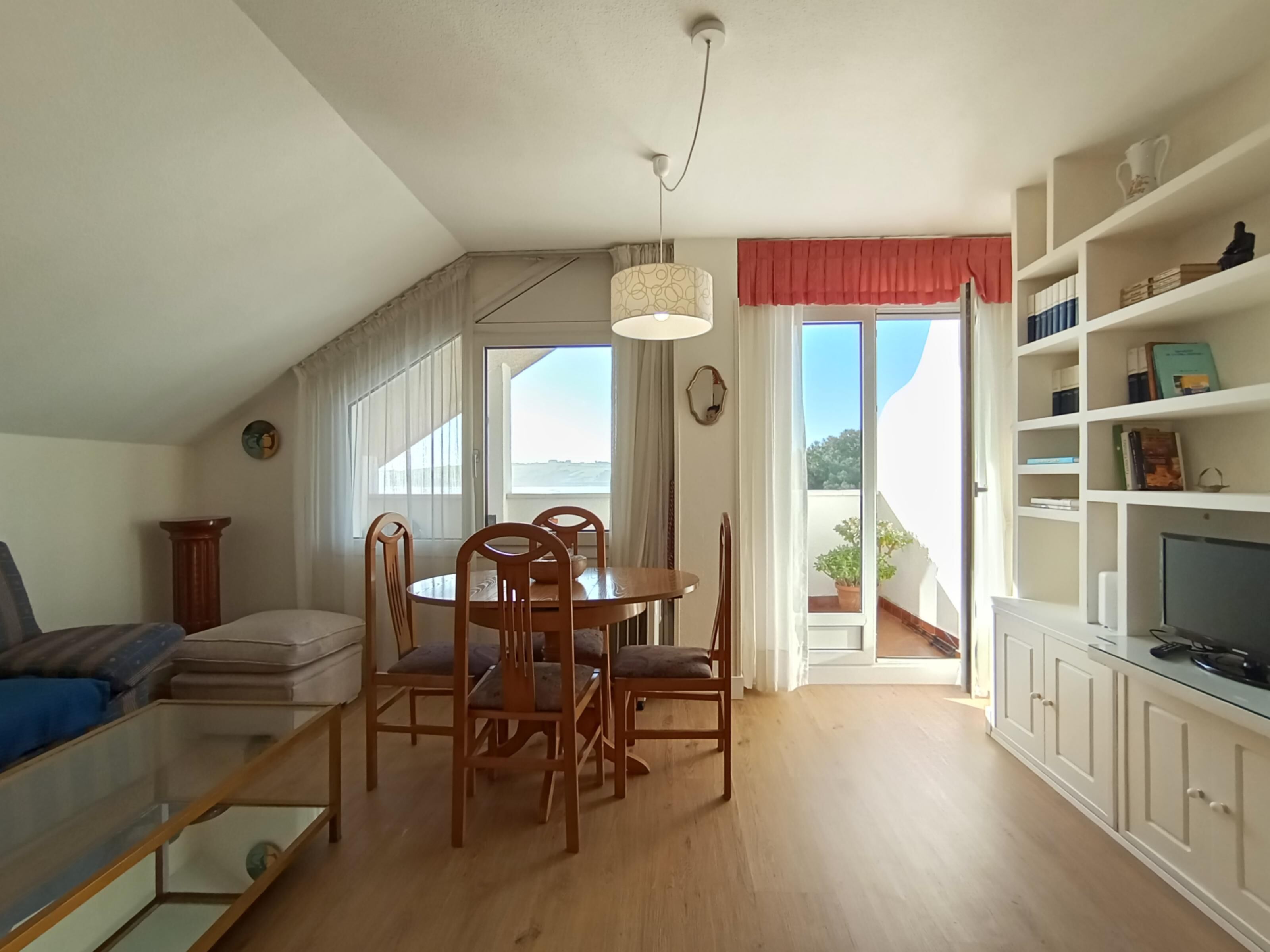 Un espace de vie compact comprenant un coin repas, un canapé, un téléviseur et un balcon avec vue.