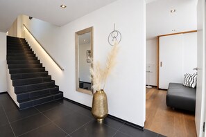 A modern interior with a staircase, a large mirror, a decorative vase, and a minimalist living area.