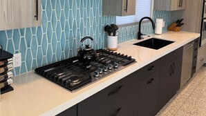 Uma cozinha moderna com fogão a gás, armários pretos e um revestimento de parede azul com padrão.