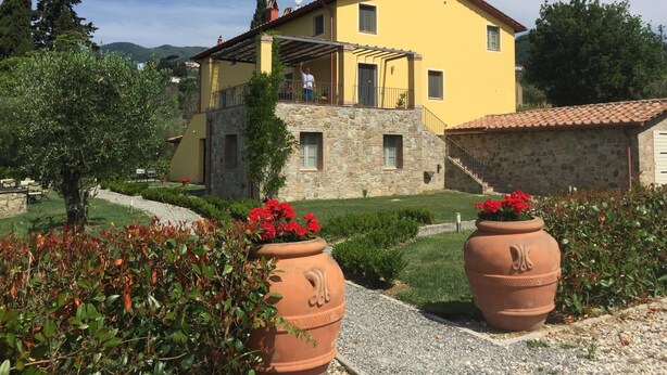A two-story yellow building with a stone base, a balcony, and a stone staircase leading to the upper floor. - Apartment in Tuscany With Scenic Pool Views (Capannori)
