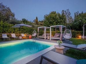 Ein Swimmingpool mit Liegestühlen, einer Hängematte und einer überdachten Sitzgruppe.