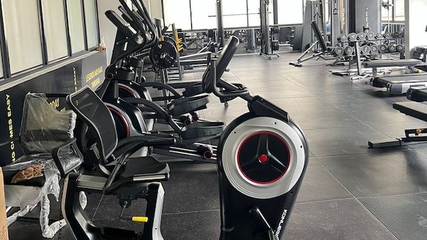 Un gimnasio con diverso equipo de ejercicio, amplias ventanas y un diseño de techo moderno.