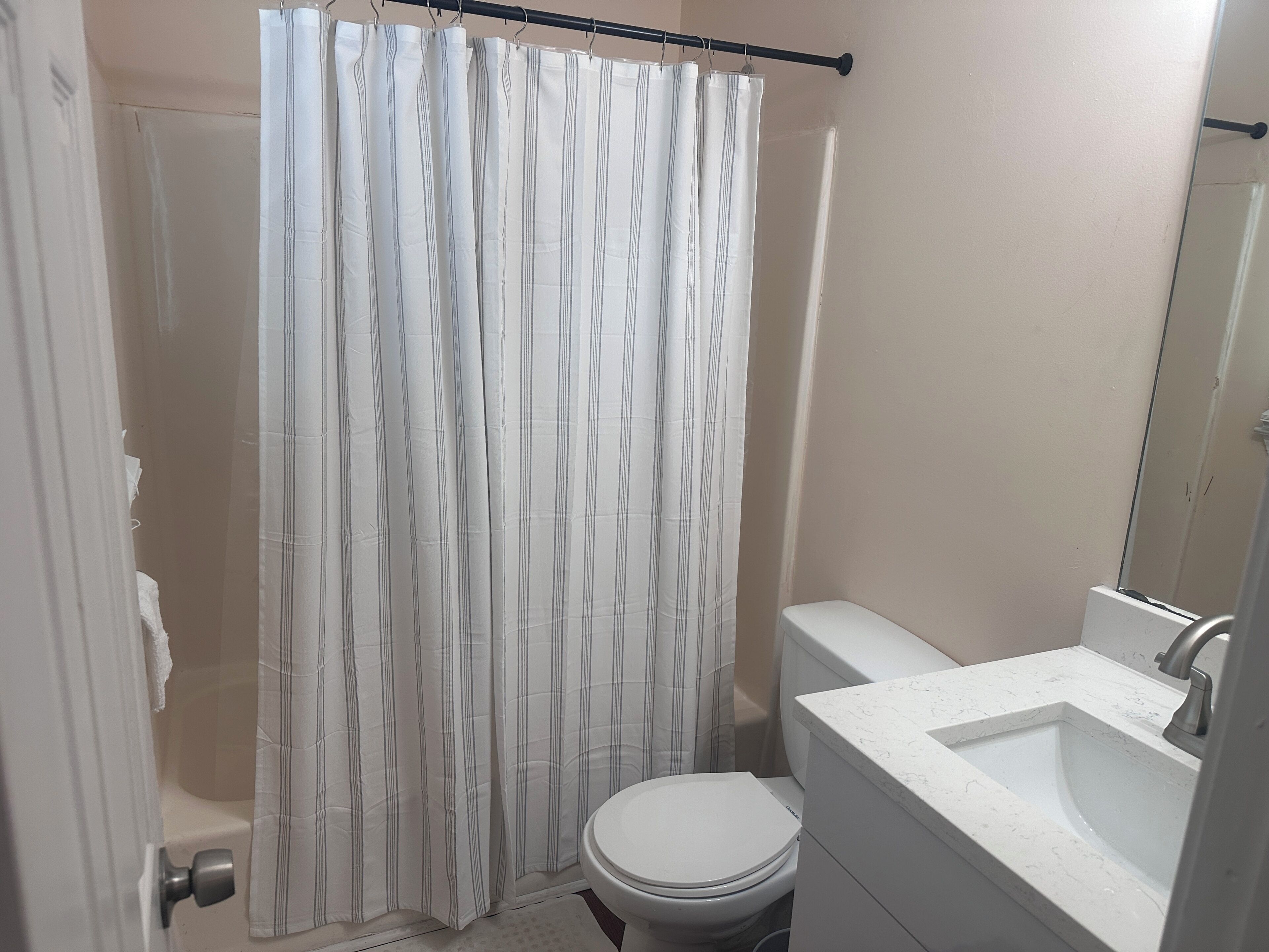 Ein Badezimmer mit Duschvorhang, Toilette und Waschbecken.