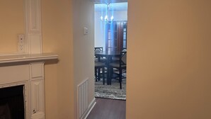 A hallway leading to a dining area with a chandelier, a fireplace, and a radiator. - 2BR Townhome Near Hospitals Free Parking Wi-Fi  (Norcross)