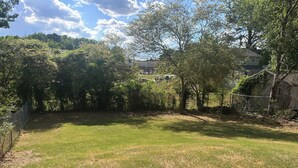A grassy backyard with trees and a fence. - 2BR Townhome Near Hospitals Free Parking Wi-Fi  (Norcross)