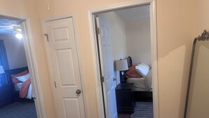 A bedroom with a bed, nightstand, lamp, and a mirror. - 2BR Townhome Near Hospitals Free Parking Wi-Fi  (Norcross)