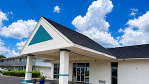A building with a covered entrance, a visible sign, and a parking lot. - Bayou Inn (Jennings)