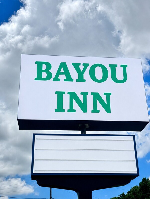 A signboard with 'BAYOU INN' written in green letters on a white background.