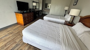 A hotel room with two beds, a desk, a television, and a mirror. - Bayou Inn (Jennings)