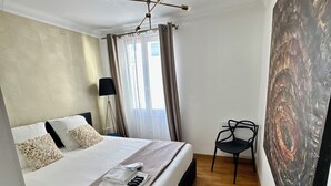 A hotel room with a bed, a chair, a painting, and a ceiling light fixture. - Luxury Apartment Paris Trocadero - 2 bedrooms 80m2 (Paris)