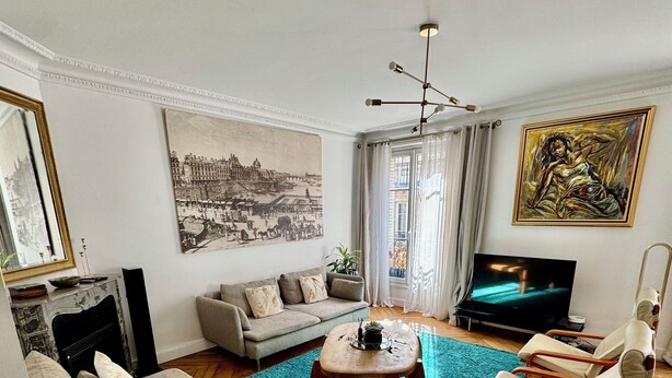 A living room with a sofa, a coffee table, a TV, and artwork on the walls. - Luxury Apartment Paris Trocadero - 2 bedrooms 80m2 (Paris)