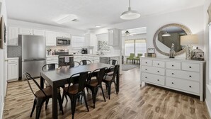 A modern kitchen with white cabinetry, a dining table with chairs, and a large mirror above the dresser. - Cozy Downtown Home W/ Beautiful City Views! (Houston)